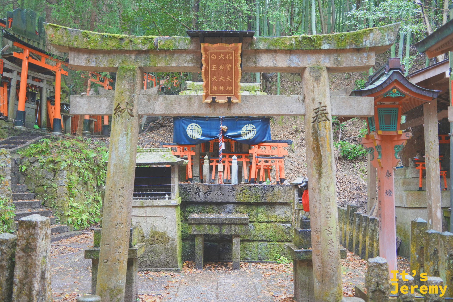 苔蘚包覆的石鳥居小祠，後方可見橙紅色的大鳥居