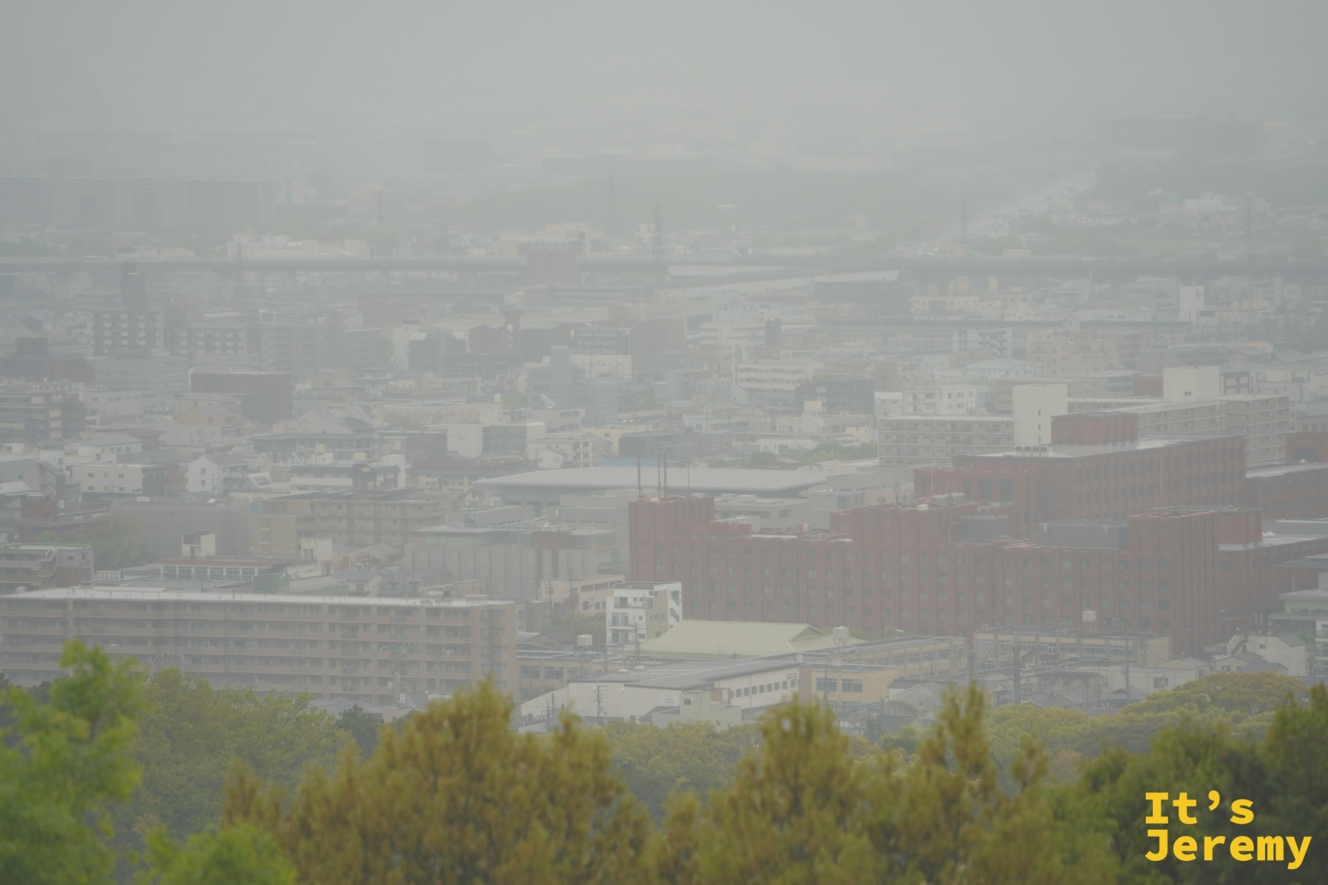 從山腰俯瞰京都市區，雨霧中的城市輪廓，有種水墨畫的氣息