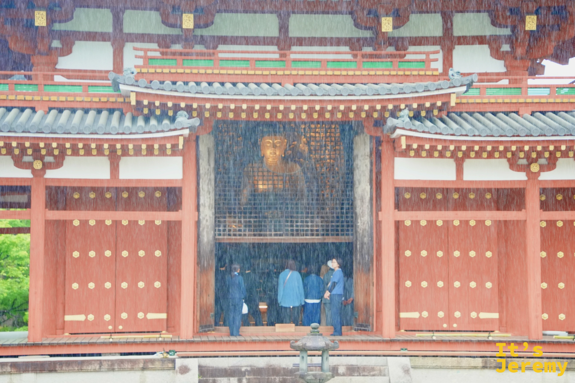重雨中的鳳凰堂正門，隱約可見堂內阿彌陀如來坐像的金色身影