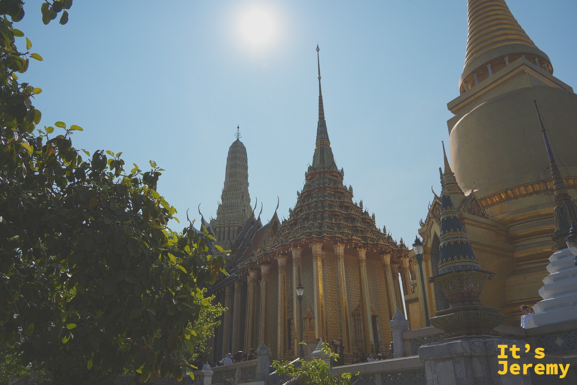樹蔭前景下的金色 Phra Si Rattana Chedi 與背後彩色 Phra Mondop 藏經閣