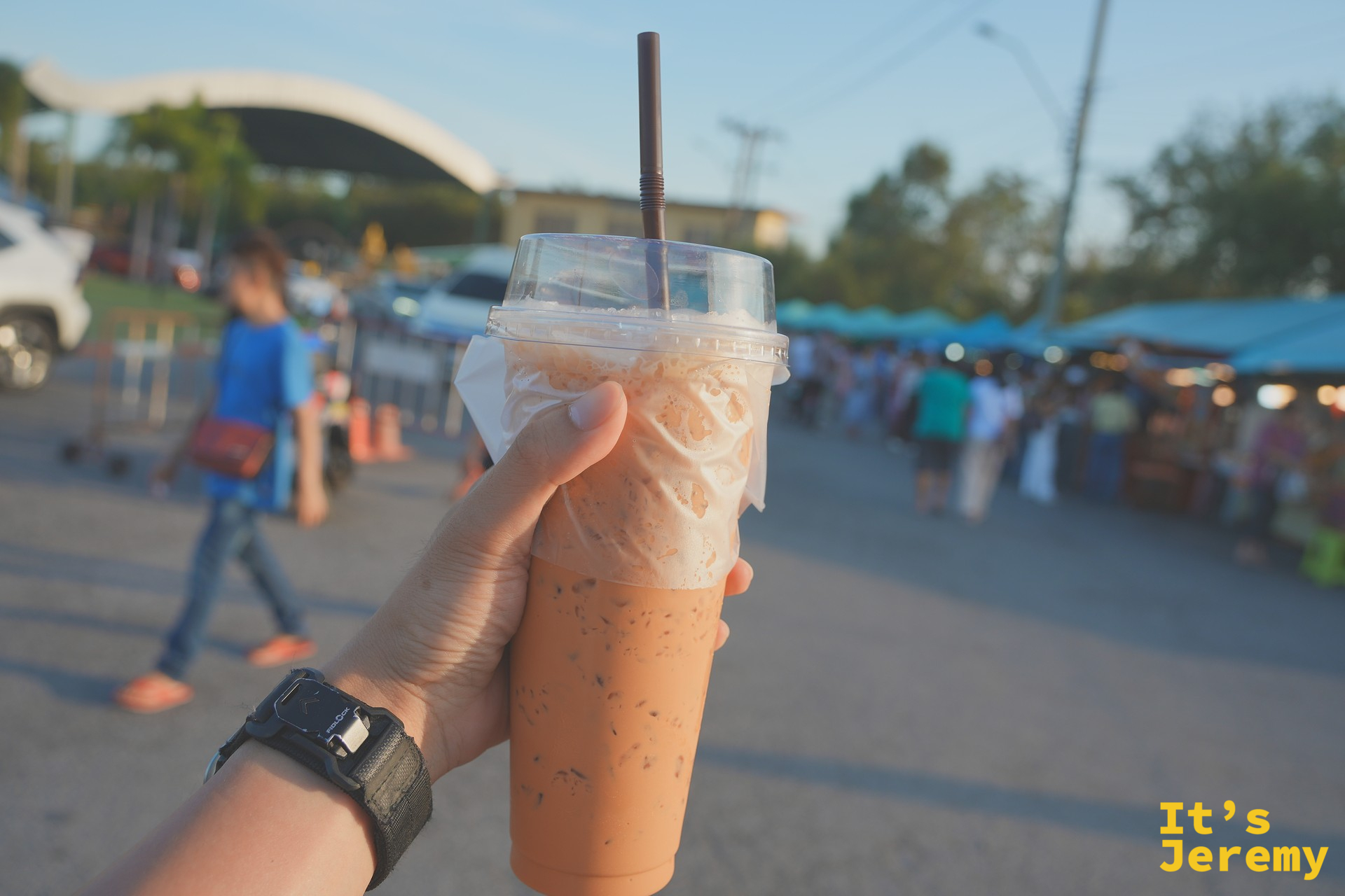 出園前手上的泰式奶茶，背景是夕陽下的市集