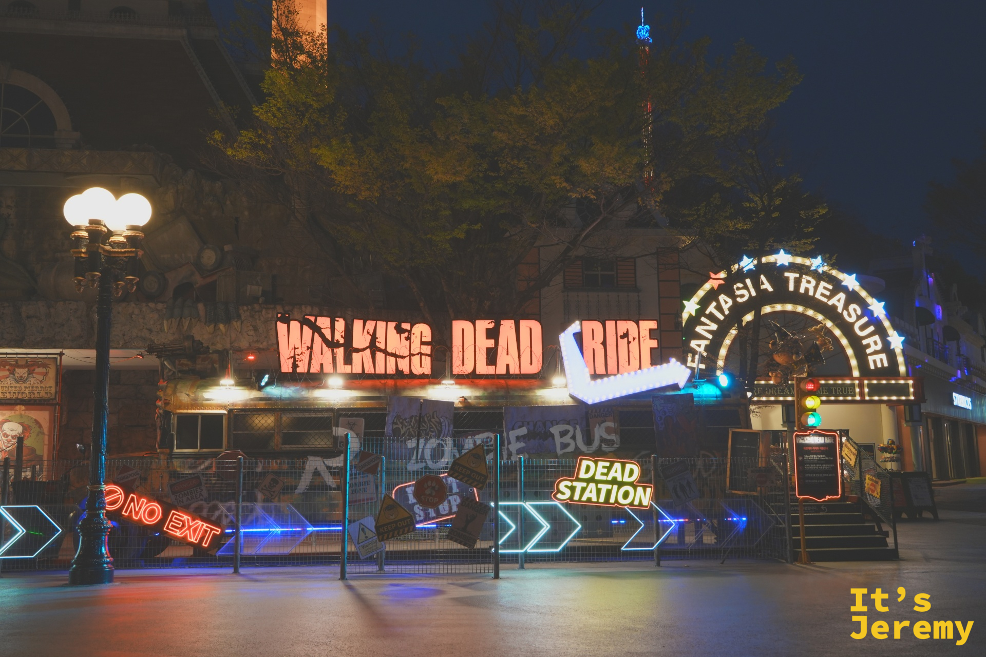 Walking Dead Ride 主題區的紅色霓虹招牌,右側有「FANTASIA TREASURE」拱門,地面散落「NO EXIT」、「DEAD STATION」霓虹道具,左邊是一盞歐式雙球路燈