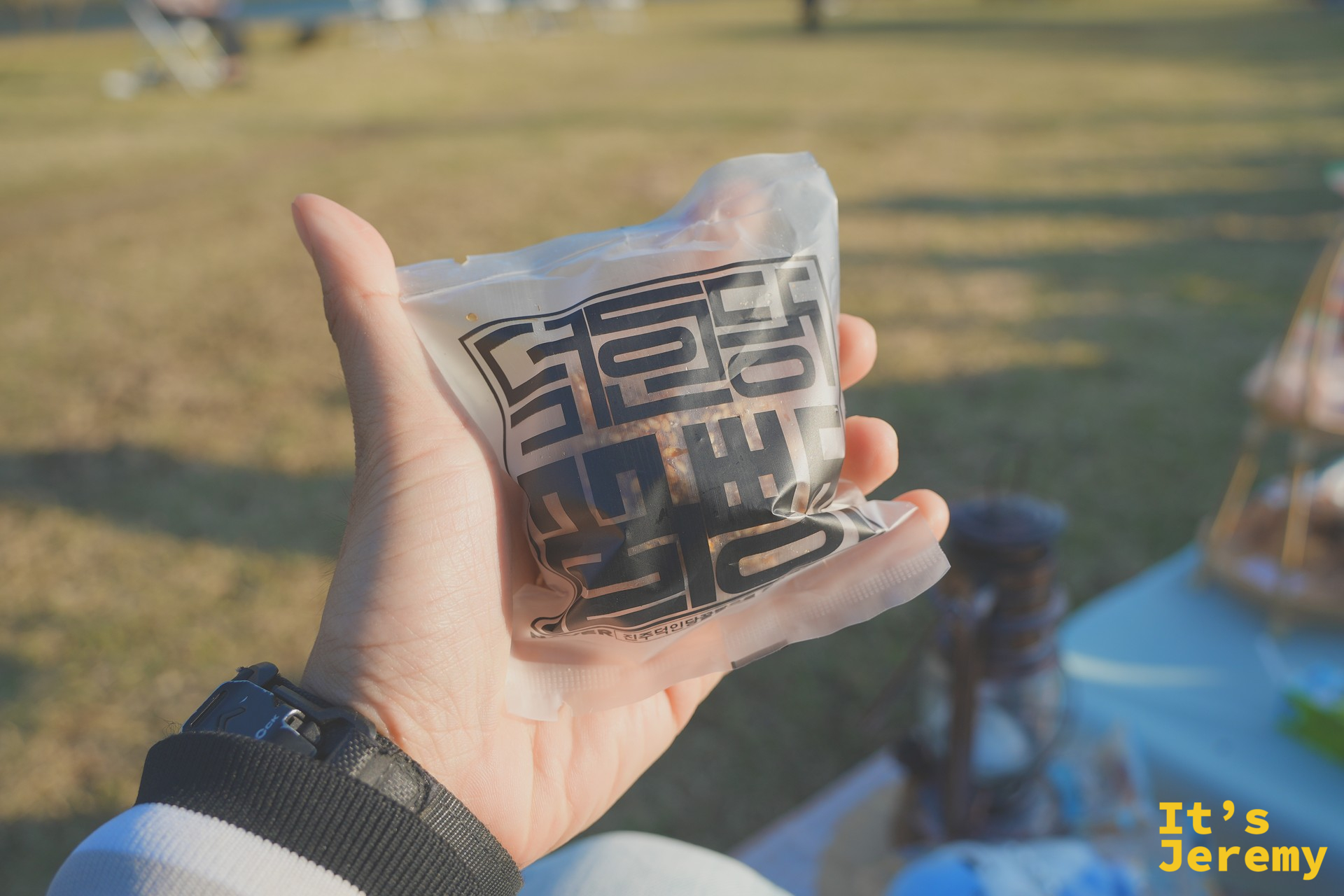 手持一包晉州在地風味零食,草地上的輕食下午茶氛圍