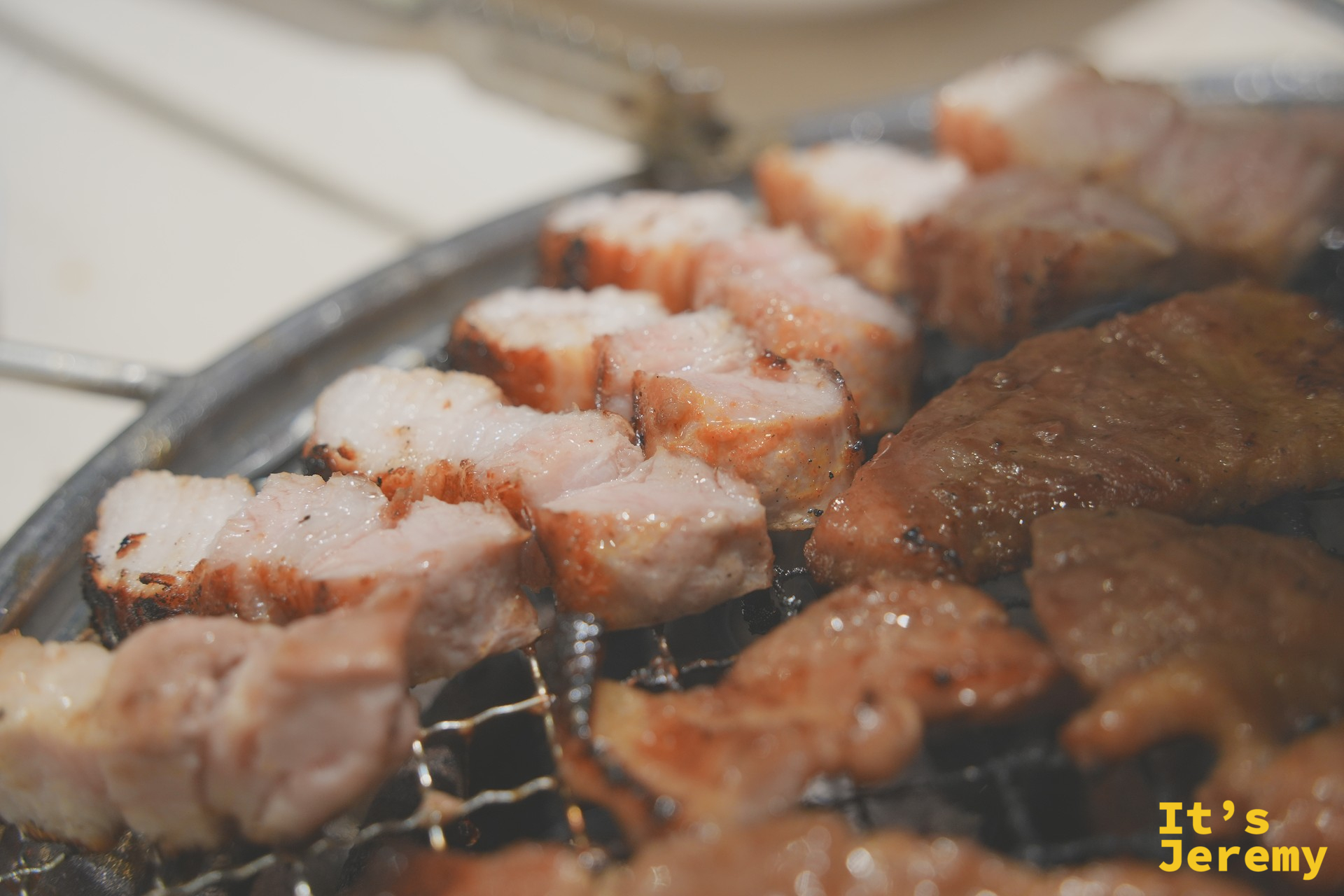 烤爐上的삼겹살與갈비肉塊,油脂滋滋冒泡,邊緣呈現漂亮的焦糖色