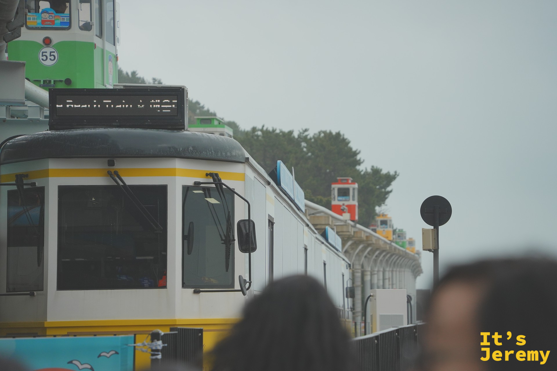 「Beach Train 해변열차」LED 字幕牌亮起，黃色與綠色海岸列車車廂並排等候出發