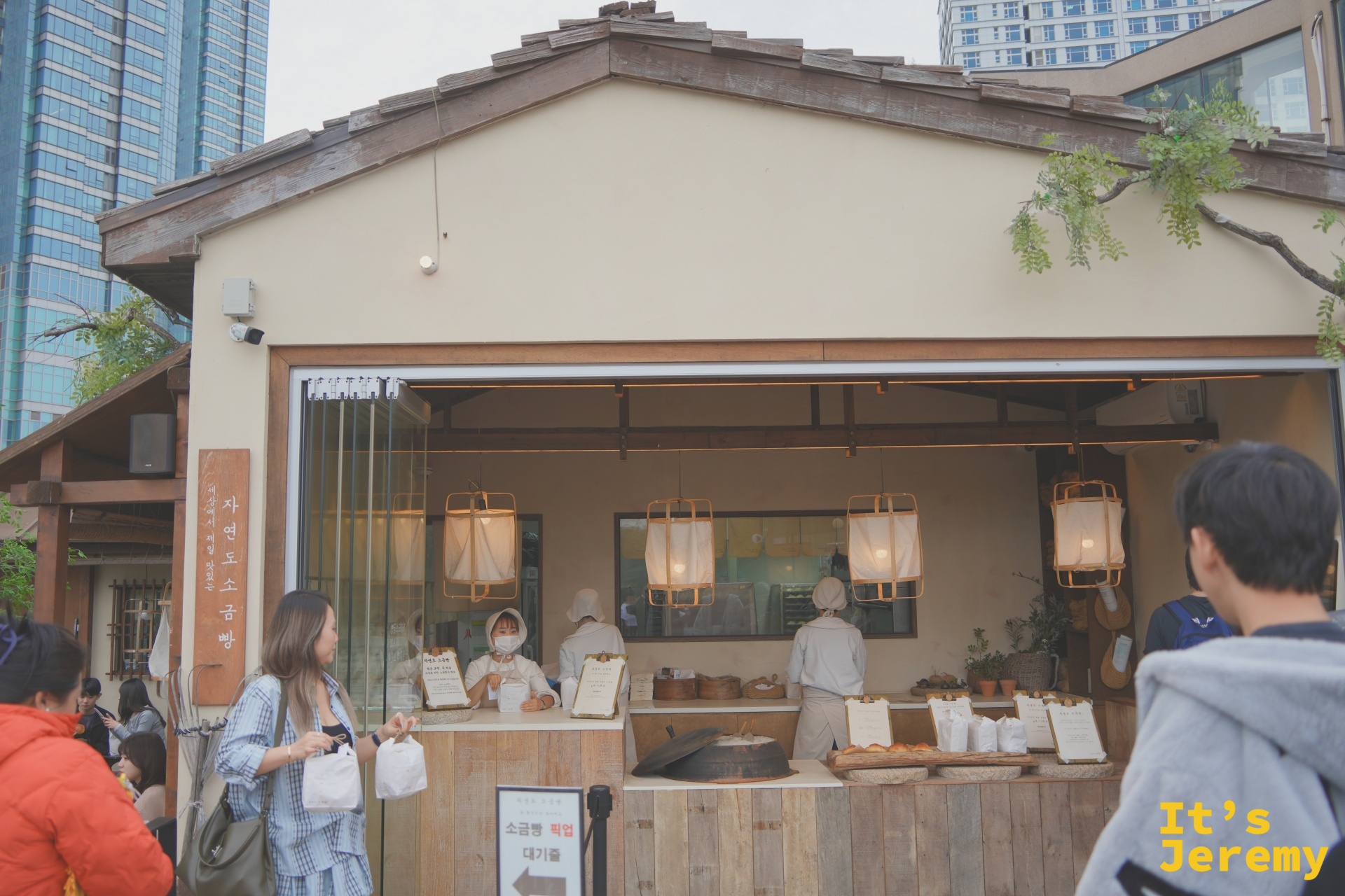 자연도 소금빵 海雲台店外觀，木造開放式攤位，暖白燈籠與排隊人潮