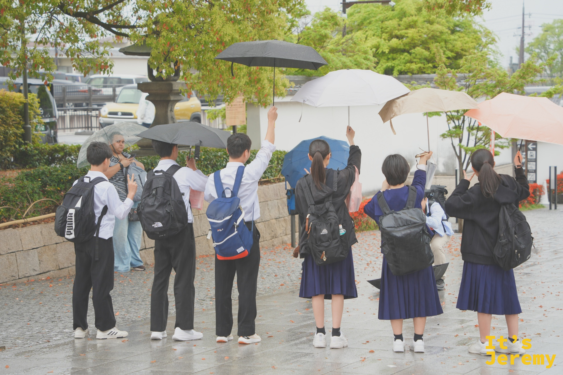 雨天的入口前，穿著制服的學生撐傘拍照留念，修學旅行來伏見稲荷是日本學生的定番行程